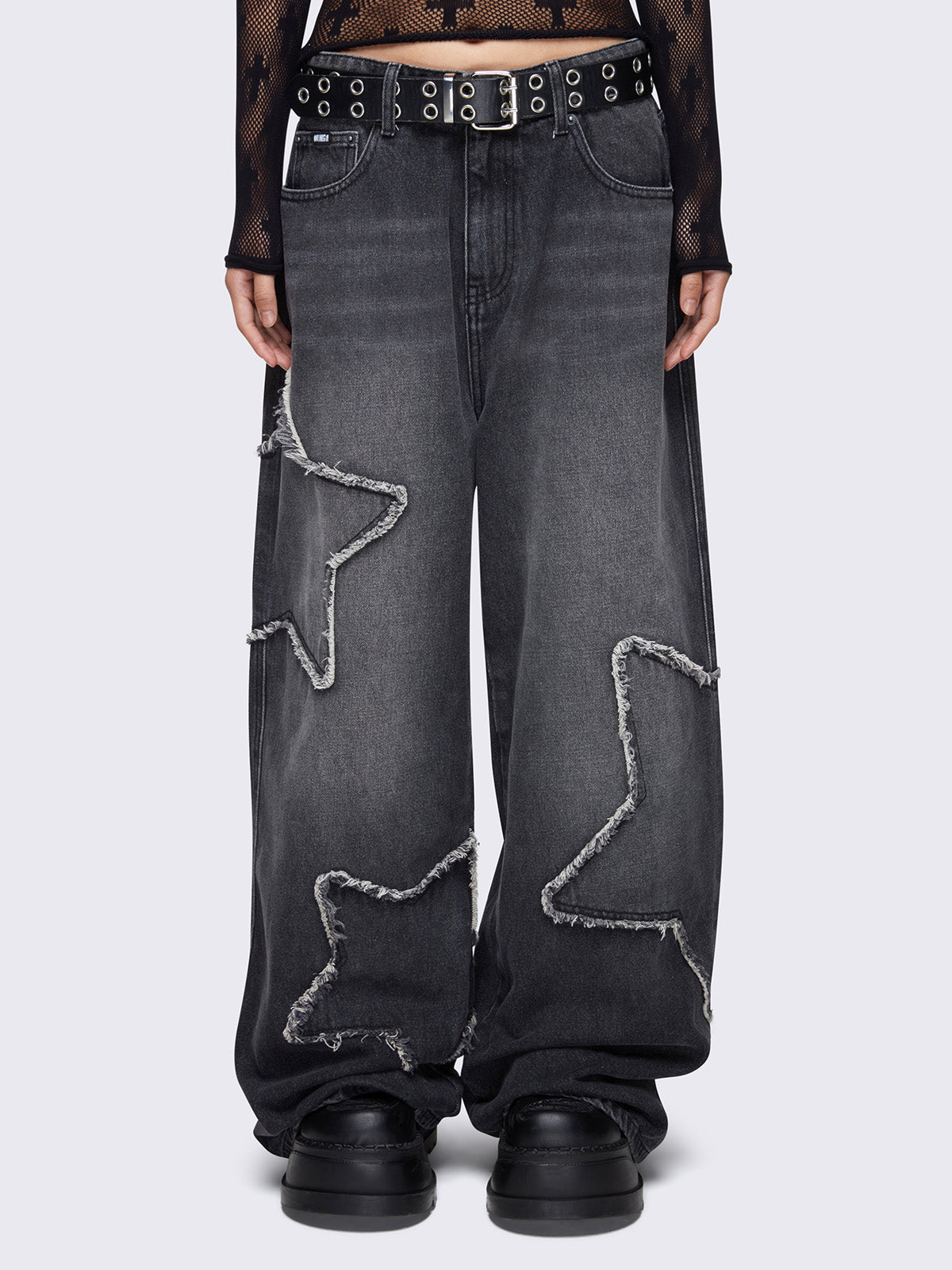Baggy jeans in washed black with frayed star patches and wide leg fit.
