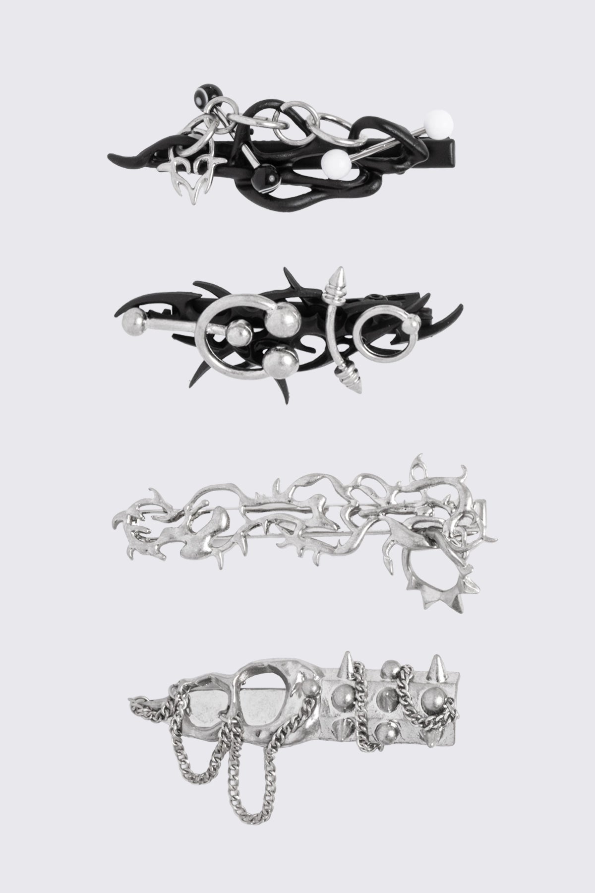 Black and silver metal hair clips with piercing, chains and sigilism details in a goth cyber style.