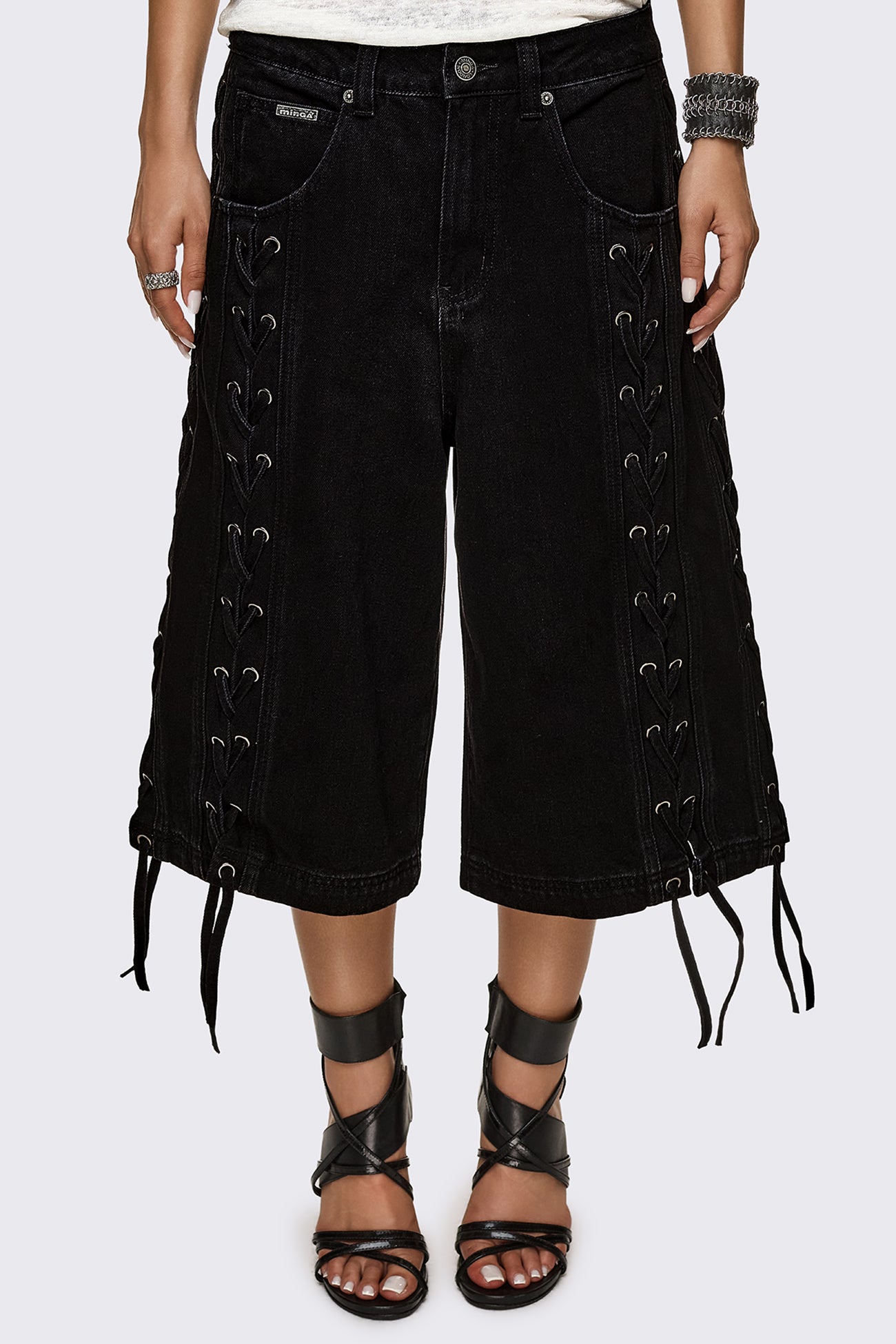 Black washed denim jorts with lace-up corset sides, baggy wide-leg fit and grunge aesthetic.