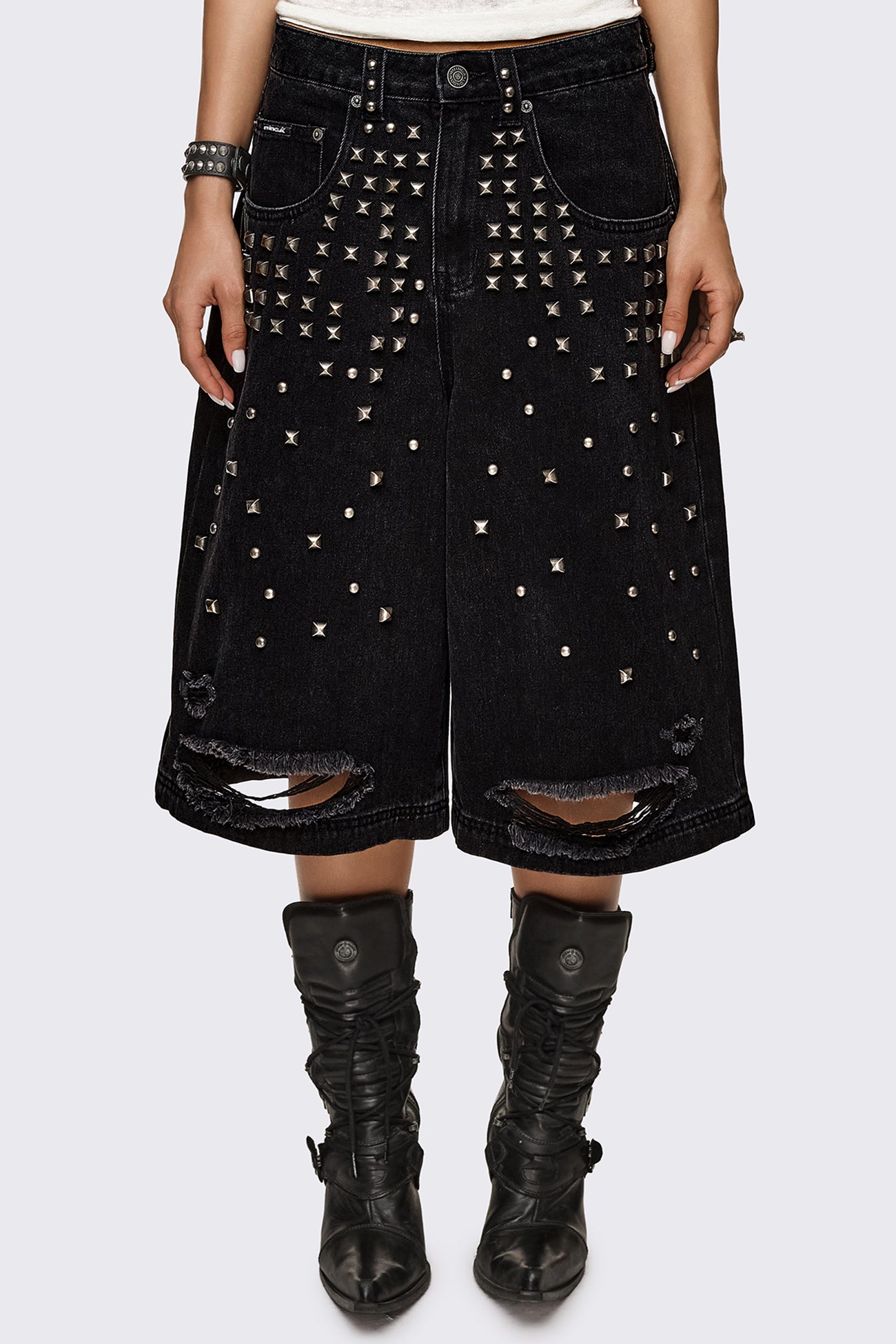 Black washed denim jorts with silver studs and ripped hems, baggy longline fit in a grunge aesthetic.