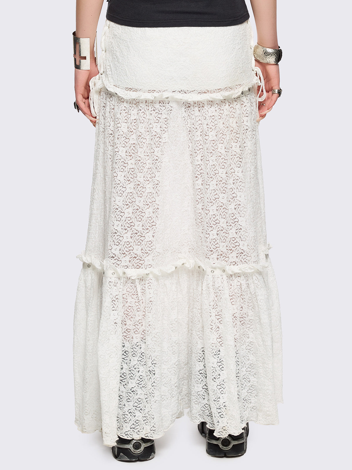 White floral lace maxi skirt with tiered lace layers with ruffles, lace-up sides with bow ties and eyelet trim details.