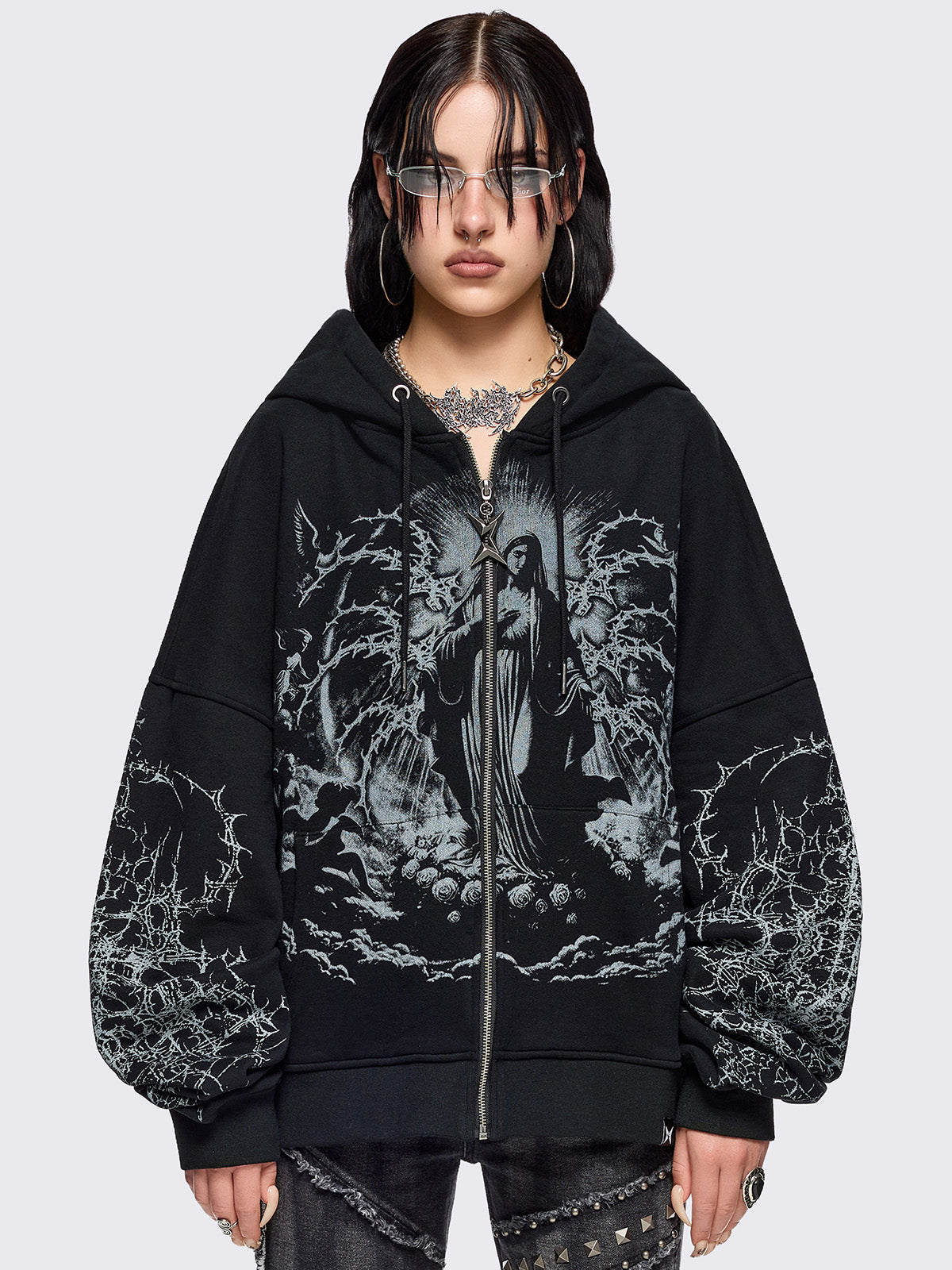 Black zip up hoodie jacket featuring a sacred figure graphic on front and thorn sleeve prints.