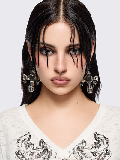 Silver dangle earrings with cross pendants featuring black stone details.