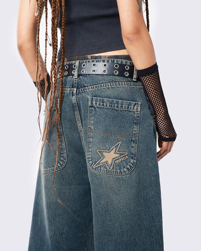 Baggy jeans in washed light blue with green overdye, Minga Star back embroidery, wide leg, regular waist, and relaxed fit. Y2K-inspired and grunge aesthetic.