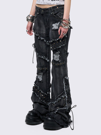 Black washed flare jeans with stud, eyelet, lace-up, and distressed details. Grunge-inspired look.