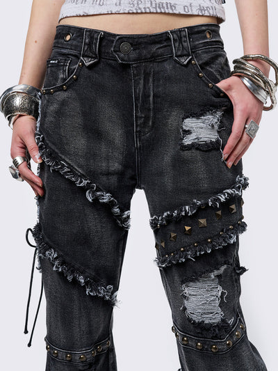 Black washed flare jeans with stud, eyelet, lace-up, and distressed details. Grunge-inspired look.