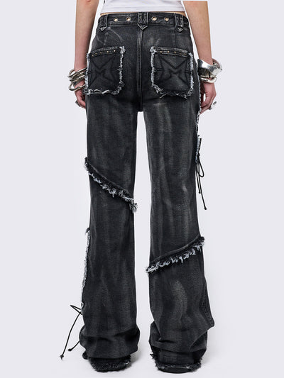 Black washed flare jeans with stud, eyelet, lace-up, and distressed details. Grunge-inspired look.