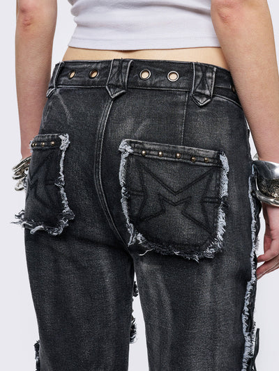 Black washed flare jeans with stud, eyelet, lace-up, and distressed details. Grunge-inspired look.