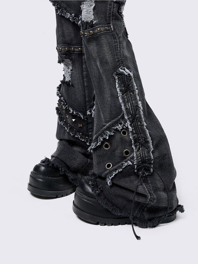 Black washed flare jeans with stud, eyelet, lace-up, and distressed details. Grunge-inspired look.
