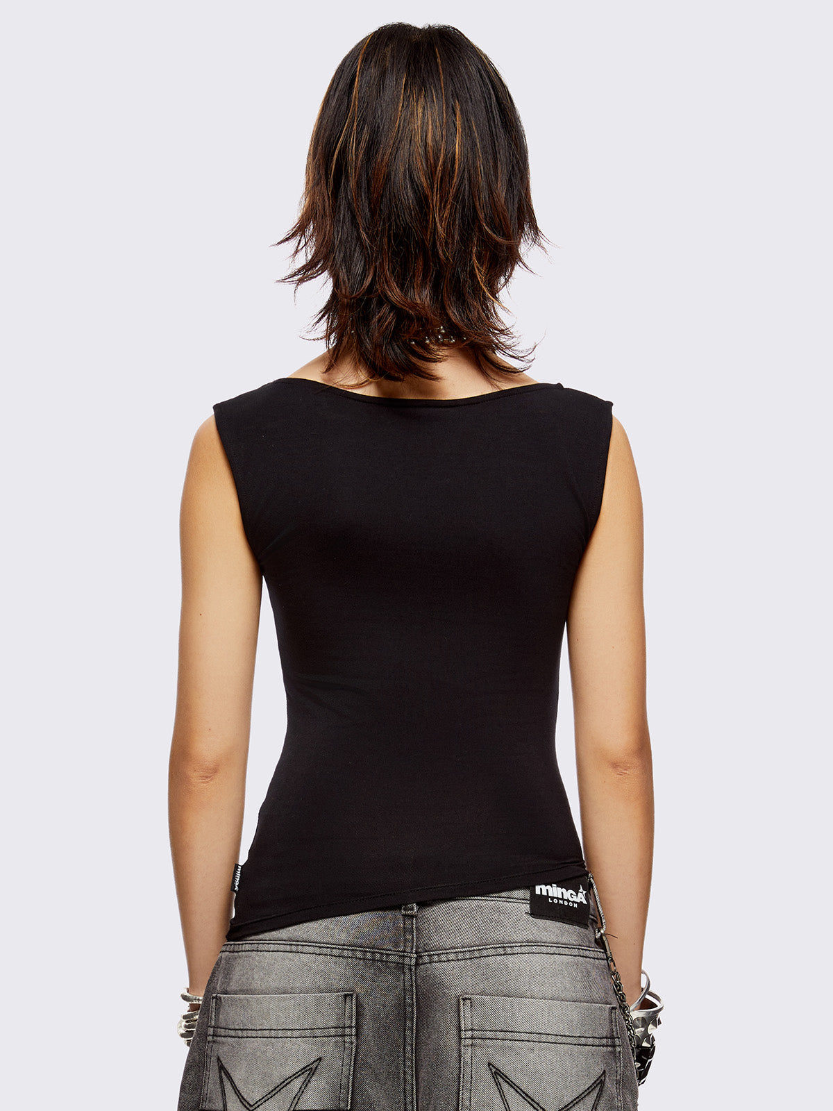 Black asymmetric top with chunky eyelets along neckline and hem and boat neckline.