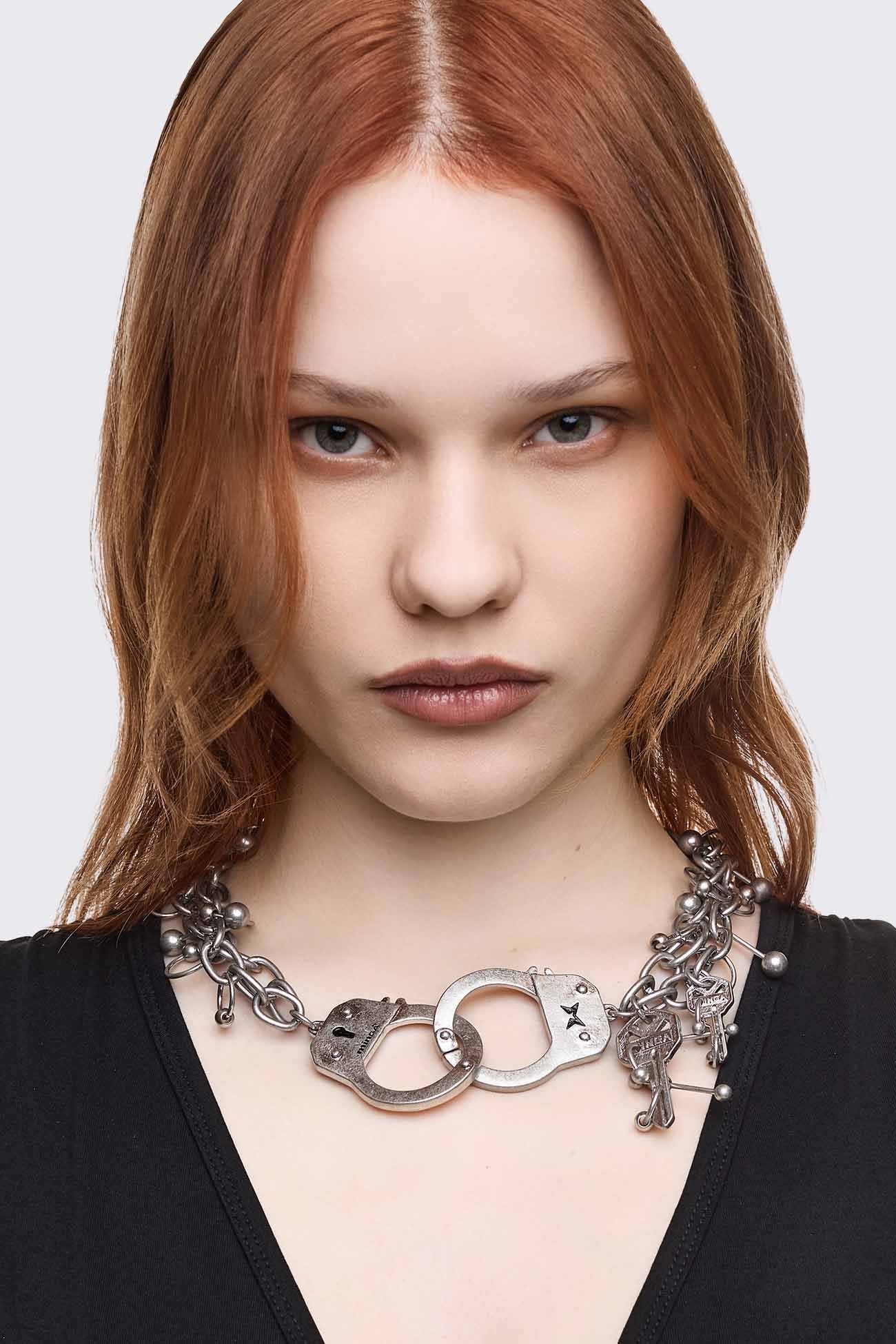 Chunky necklace in antique silver with handcuff, key and piercing charms in a grunge goth style.