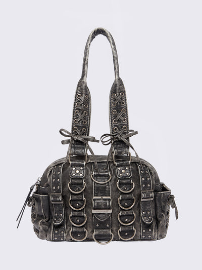 Black washed faux leather shoulder bag with multiple D-rings, buckles and hardware details, worn on shoulder with lace-up strap design.