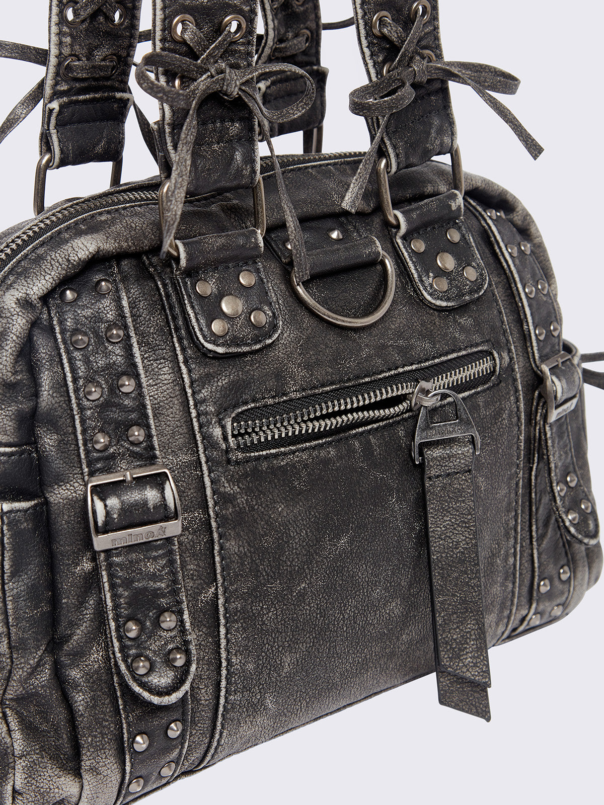 Black washed faux leather shoulder bag with multiple D-rings, buckles and hardware details, worn on shoulder with lace-up strap design.
