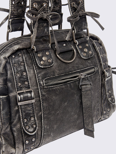 Black washed faux leather shoulder bag with multiple D-rings, buckles and hardware details, worn on shoulder with lace-up strap design.