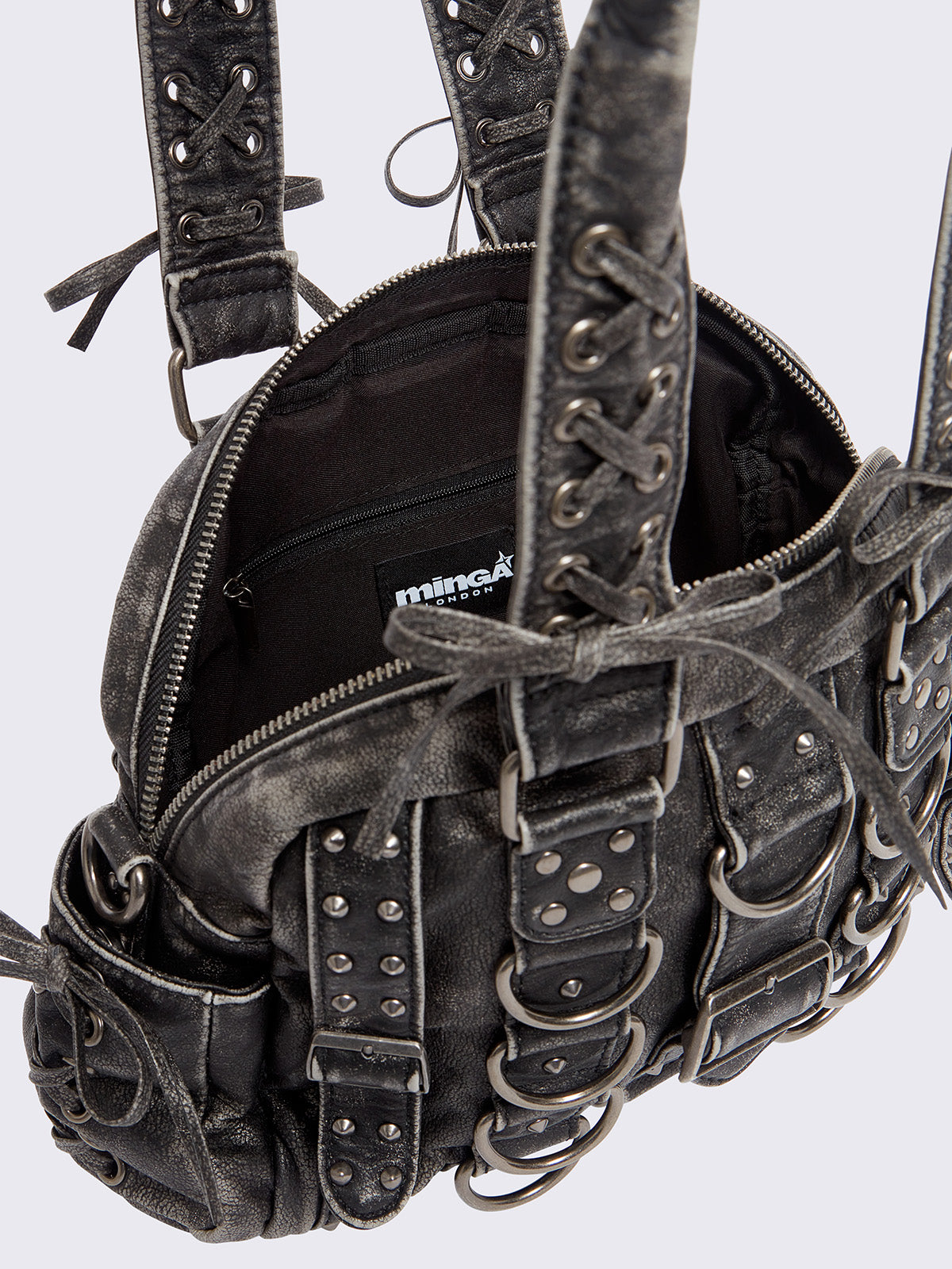 Black washed faux leather shoulder bag with multiple D-rings, buckles and hardware details, worn on shoulder with lace-up strap design.