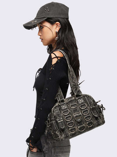Black washed faux leather shoulder bag with multiple D-rings, buckles and hardware details, worn on shoulder with lace-up strap design.