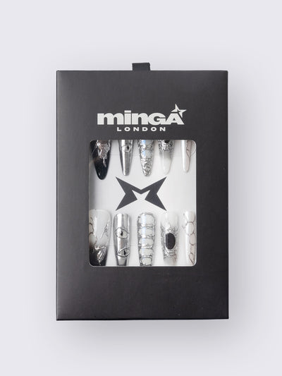 Press-on nail set in chrome and white with marble, piercing rings, chain lacing, and stiletto shape for a grunge glam look.