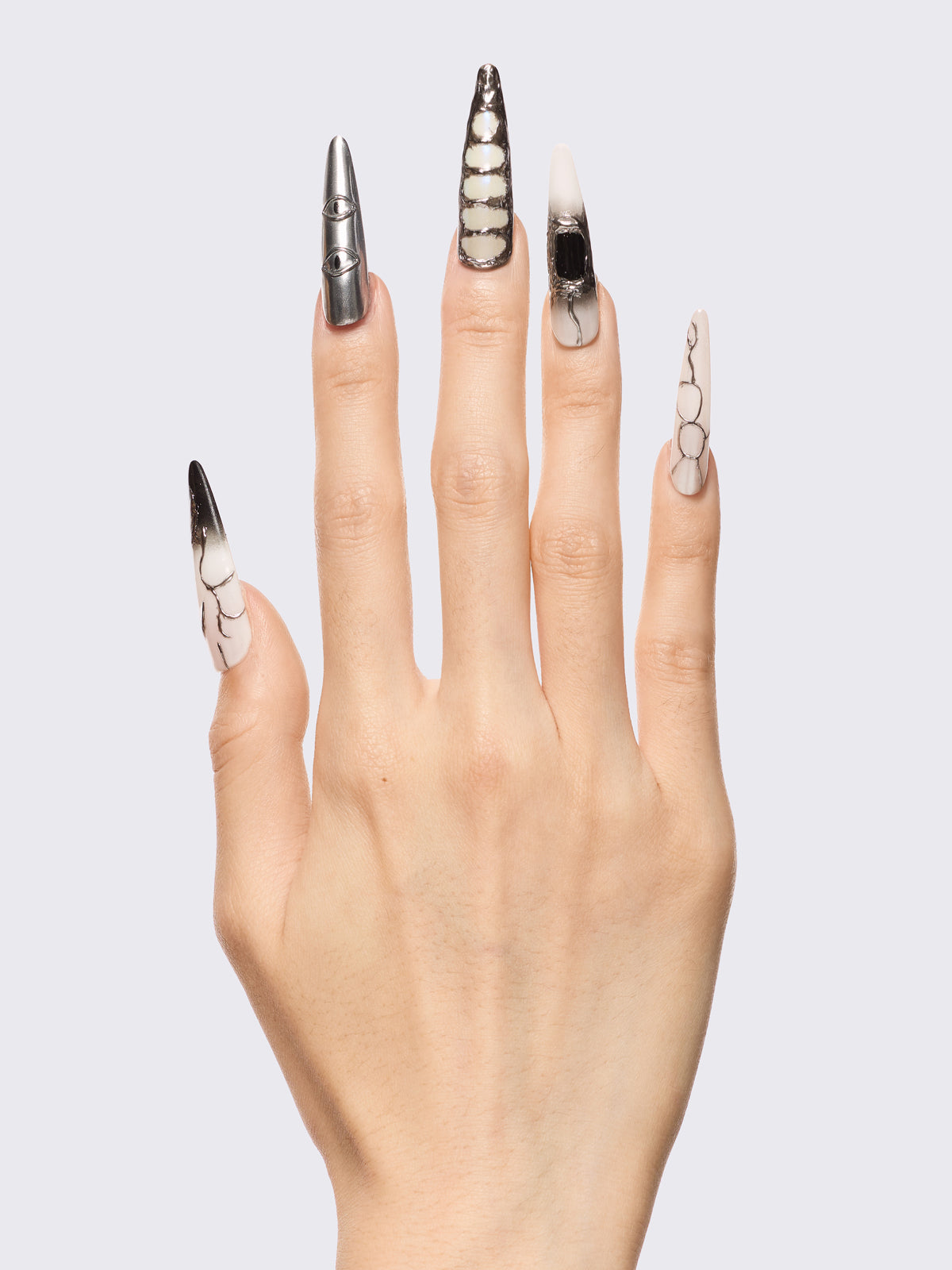Press-on nail set in chrome and white with marble, piercing rings, chain lacing, and stiletto shape for a grunge glam look.