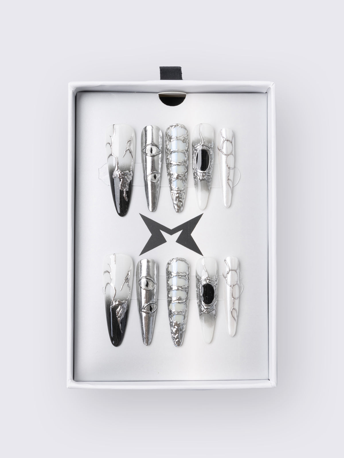 Press-on nail set in chrome and white with marble, piercing rings, chain lacing, and stiletto shape for a grunge glam look.
