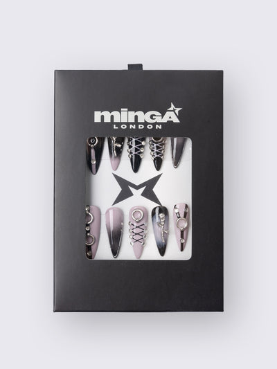 Set of stiletto press-on nails features a bold black and dusty pink ombré base, detailed with metallic piercing accents, faux corset lacing, and 3D charm embellishments. Perfect for adding edge to your outfit without a trip to the salon.