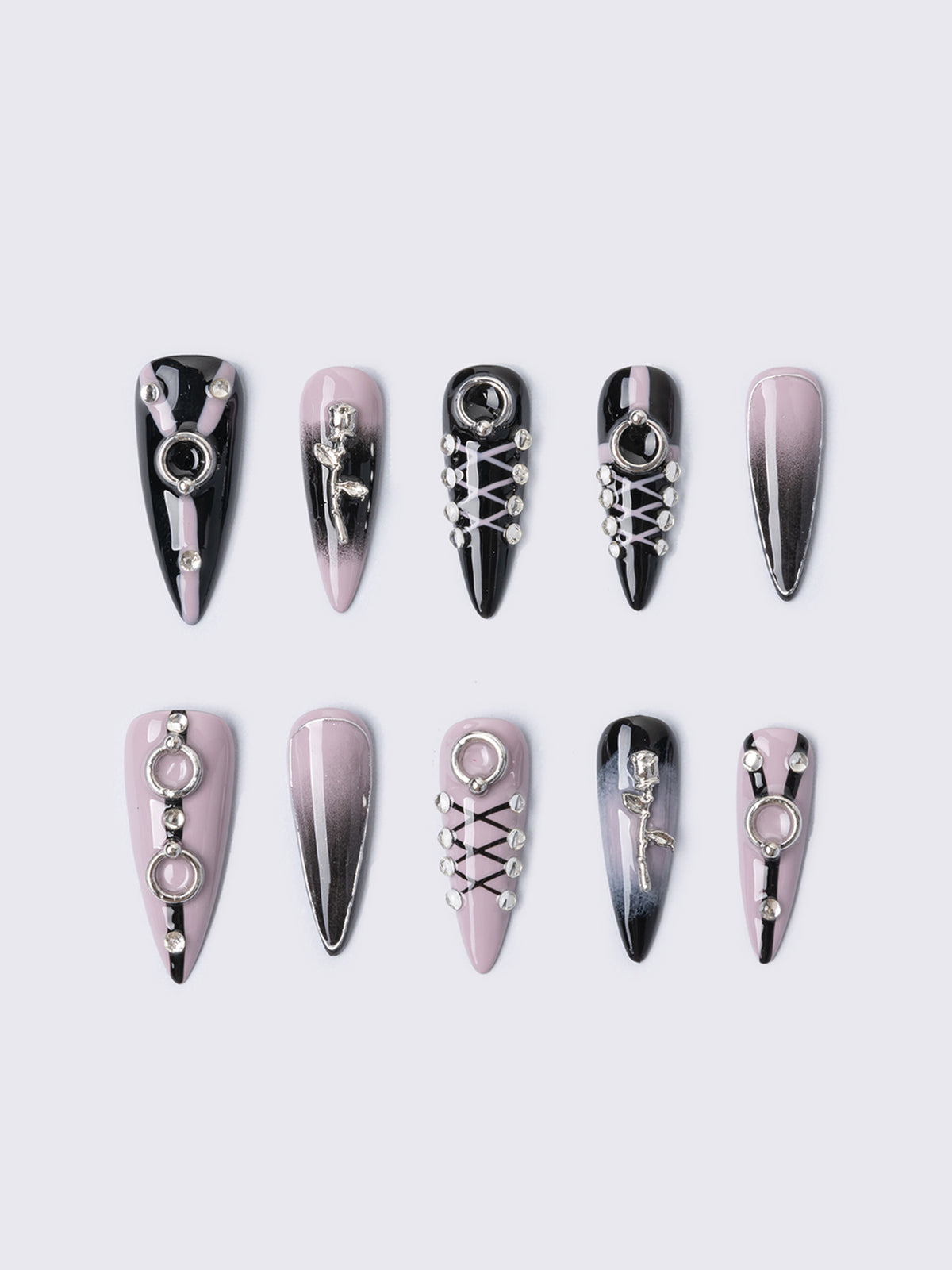 Set of stiletto press-on nails features a bold black and dusty pink ombré base, detailed with metallic piercing accents, faux corset lacing, and 3D charm embellishments. Perfect for adding edge to your outfit without a trip to the salon.
