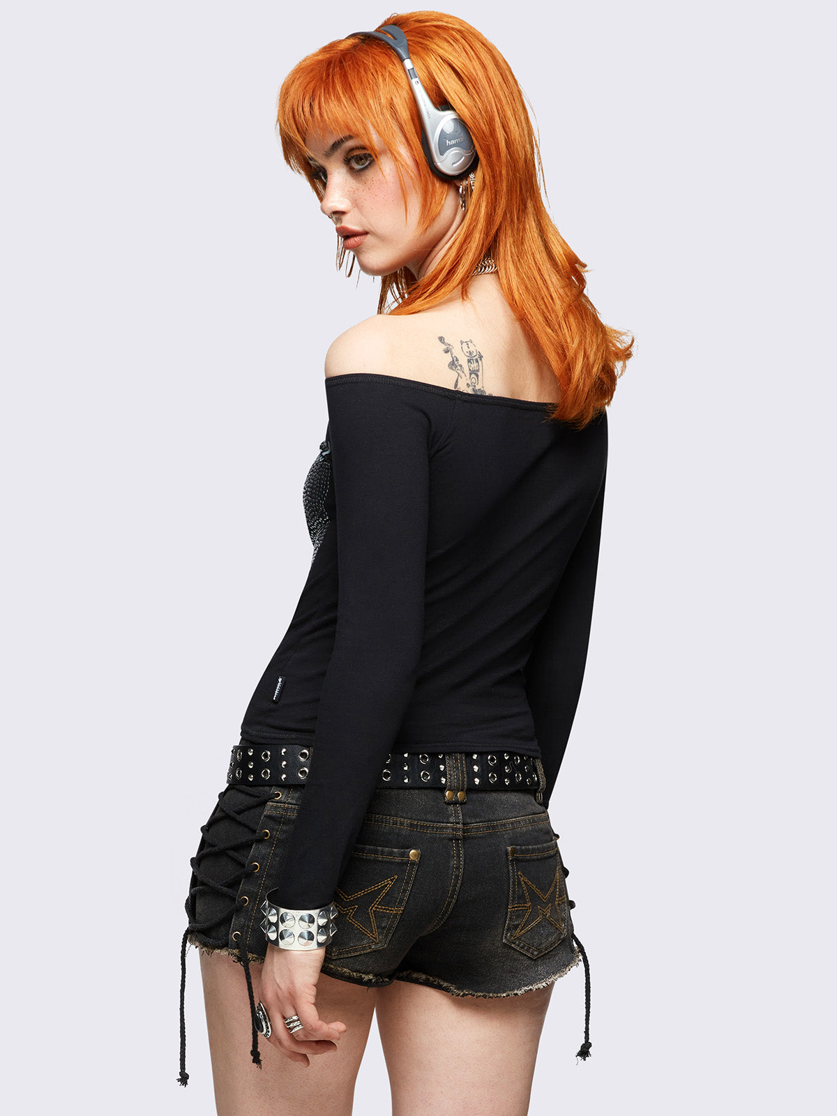 Black long sleeve off-shoulder top featuring hot fix stud wings and "Divine soul" graphic print.