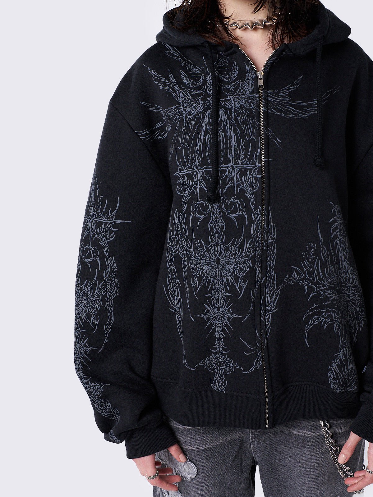 Oversized black zip-up hoodie with grunge graphic prints, drawstring hood, and ribbed trims. Y2K and acubi-inspired streetwear.