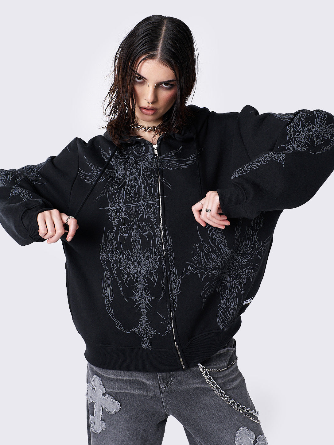 Oversized black zip-up hoodie with grunge graphic prints, drawstring hood, and ribbed trims. Y2K and acubi-inspired streetwear.