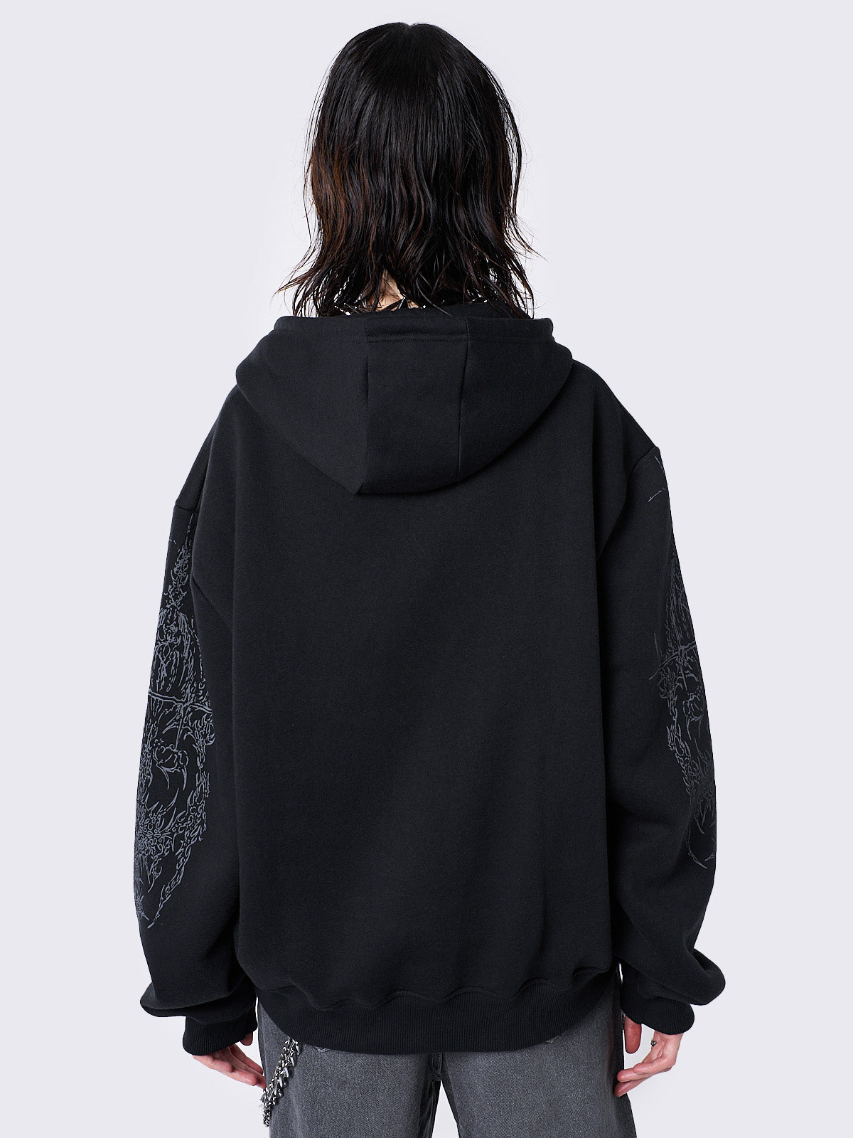 Oversized black zip-up hoodie with grunge graphic prints, drawstring hood, and ribbed trims. Y2K and acubi-inspired streetwear.