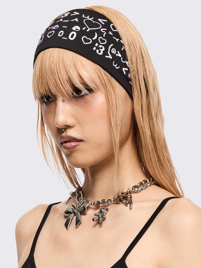 Black wide headband with white kaomoji ASCII-style graphic embroidery.