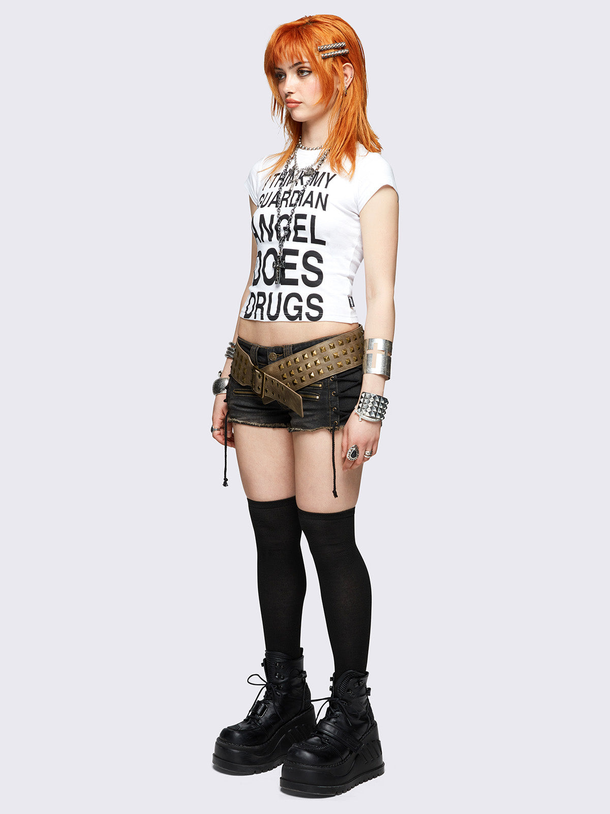 White baby tee with bold black "I think my guardian angel does drugs" front print, featuring a black cross back print.