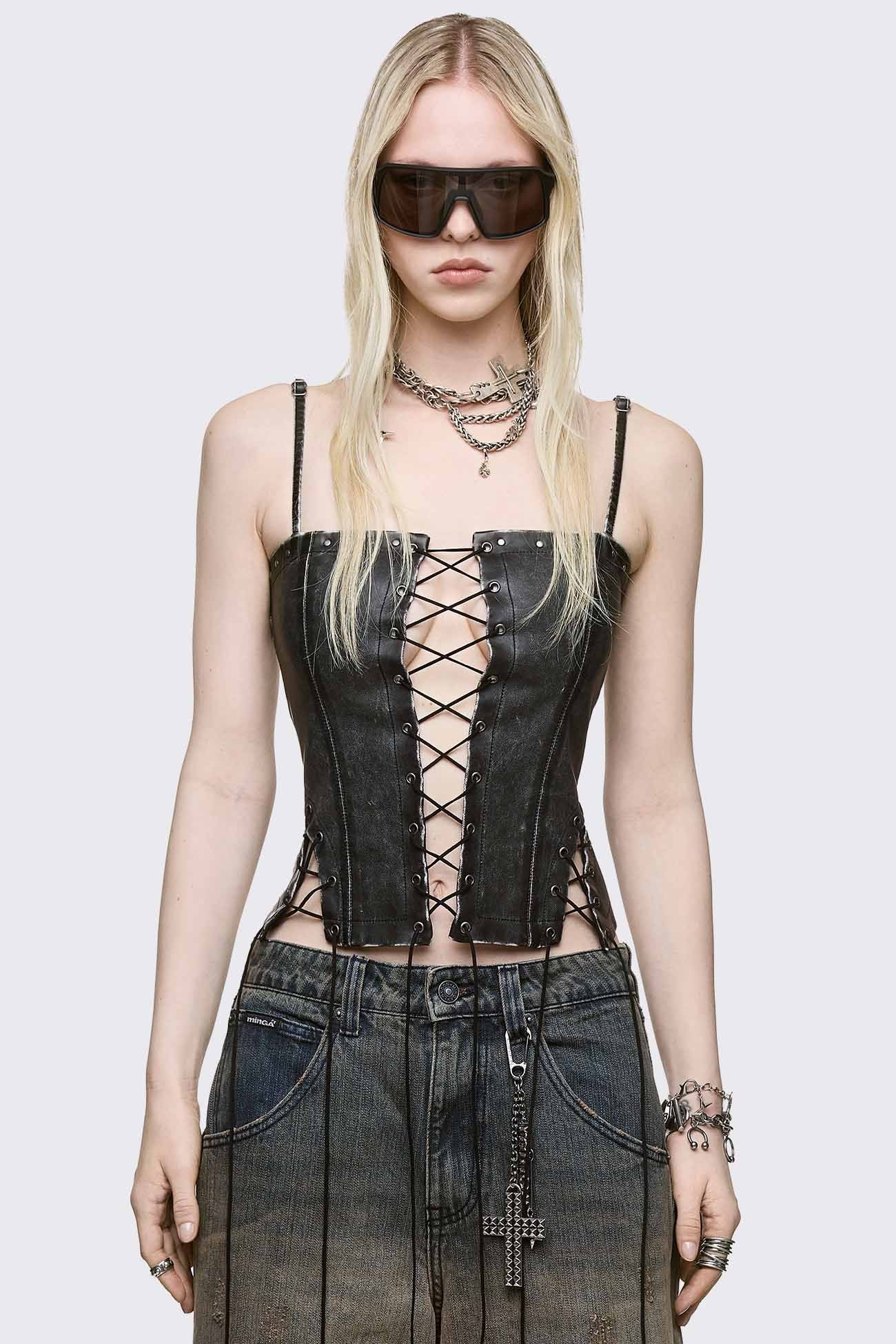 Washed faux-leather corset top featuring a central lace-up front, side cut-out lacing, and silver metal studs along the edges.