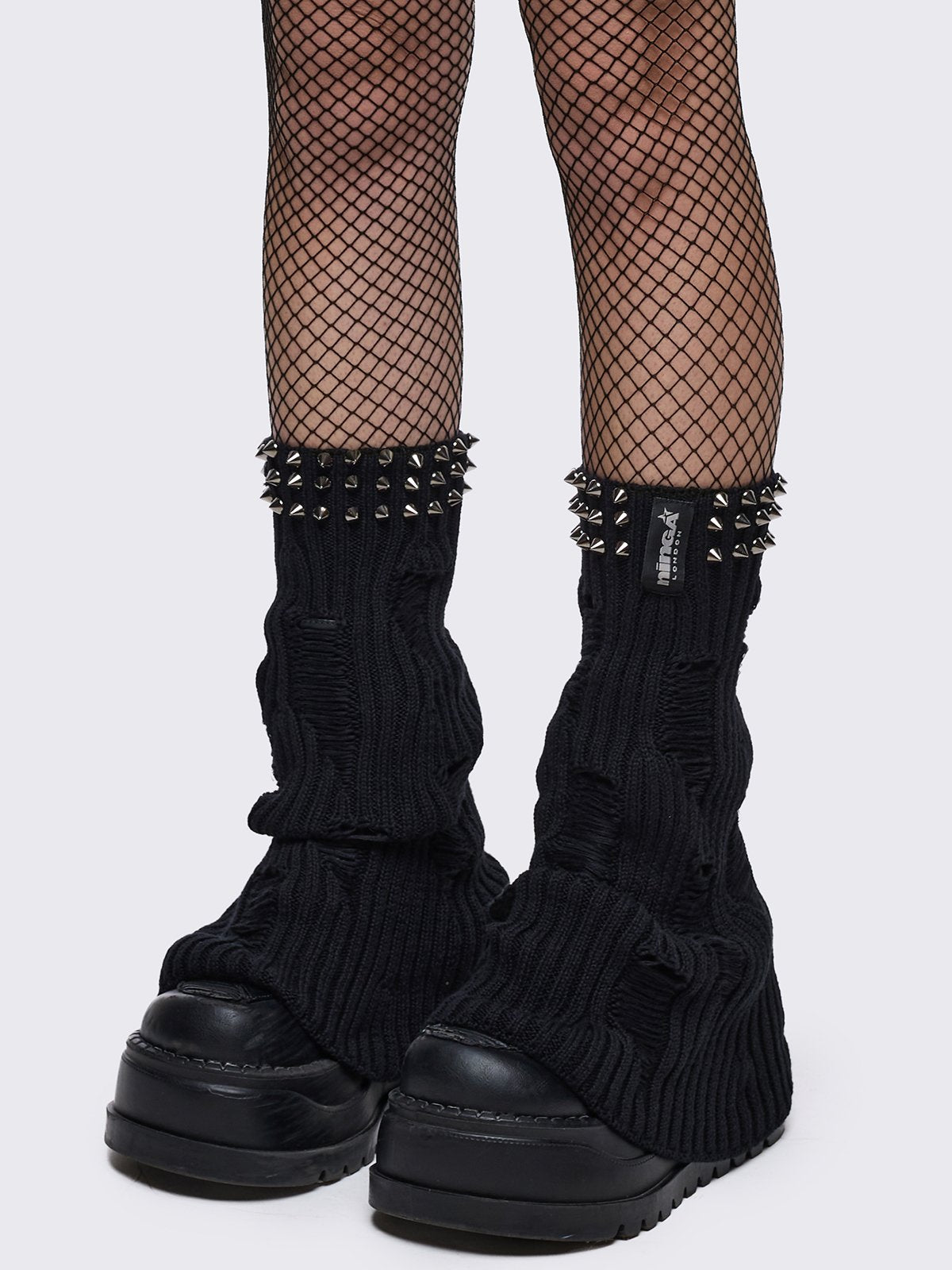 Black knitted flare leg warmers with spiked trim and distressed details.