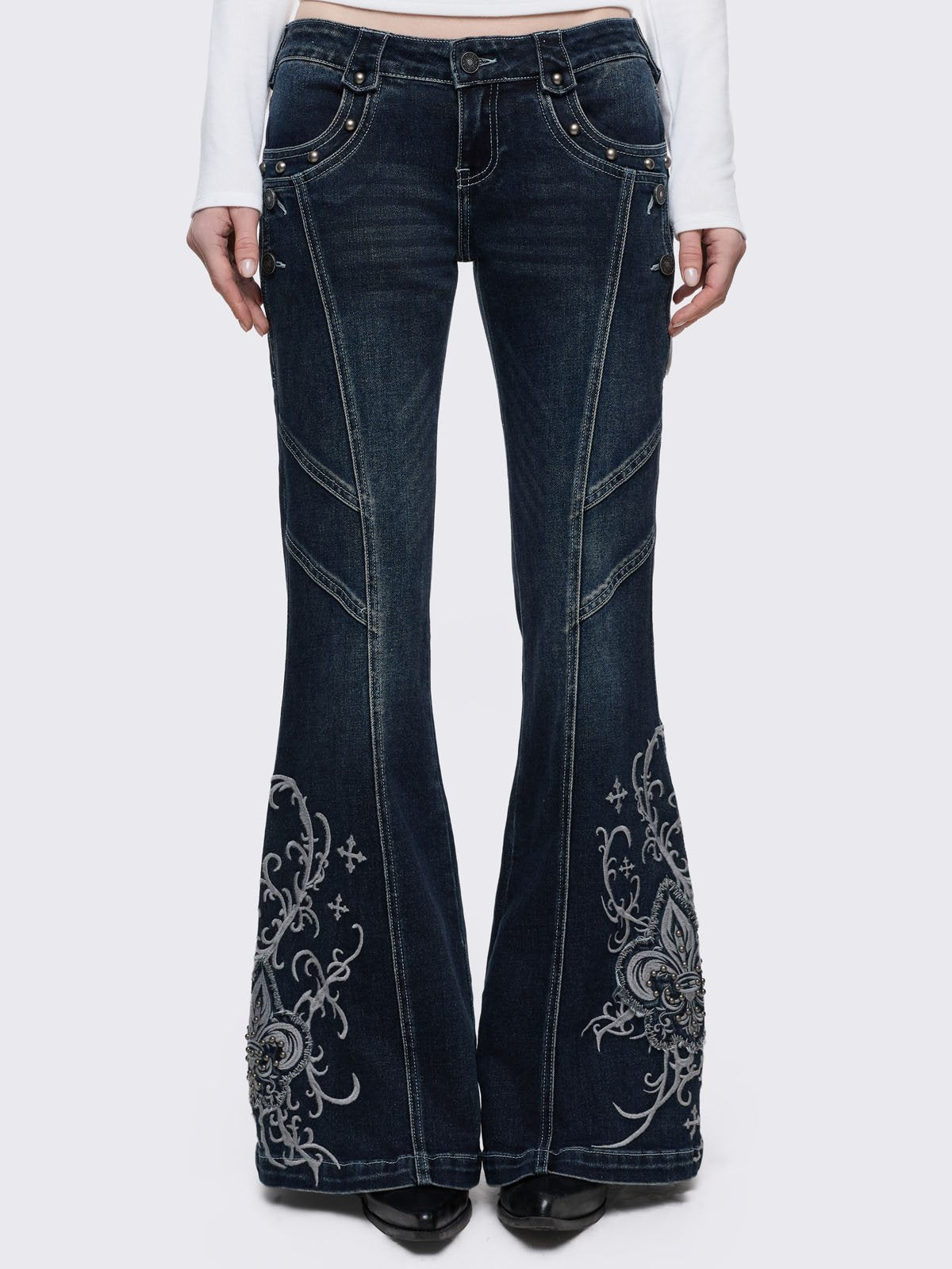 Dark blue wash flared jeans featuring gothic floral and fleur-de-lis embroidery on the lower legs and seams details. 