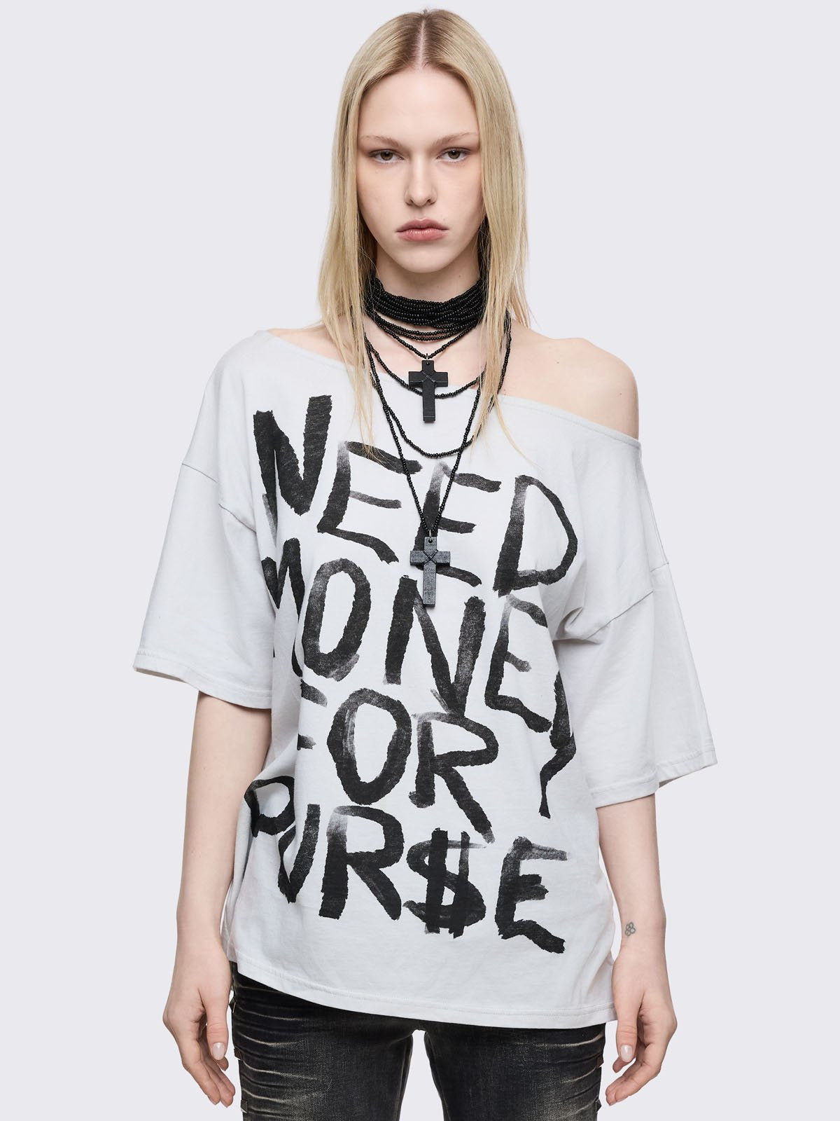 White oversized t-shirt with "Need money for pur$e" graphic front print and off-shoulder style.