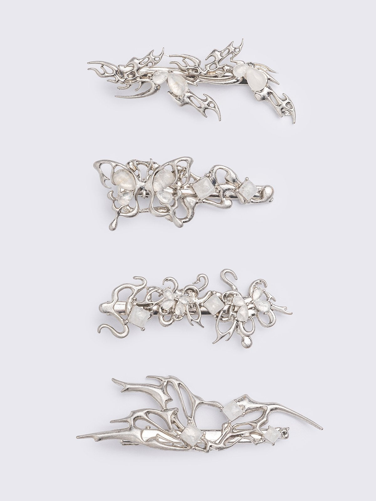 Set of 4 hair clips with butterflies and sigilism design and white stone details.