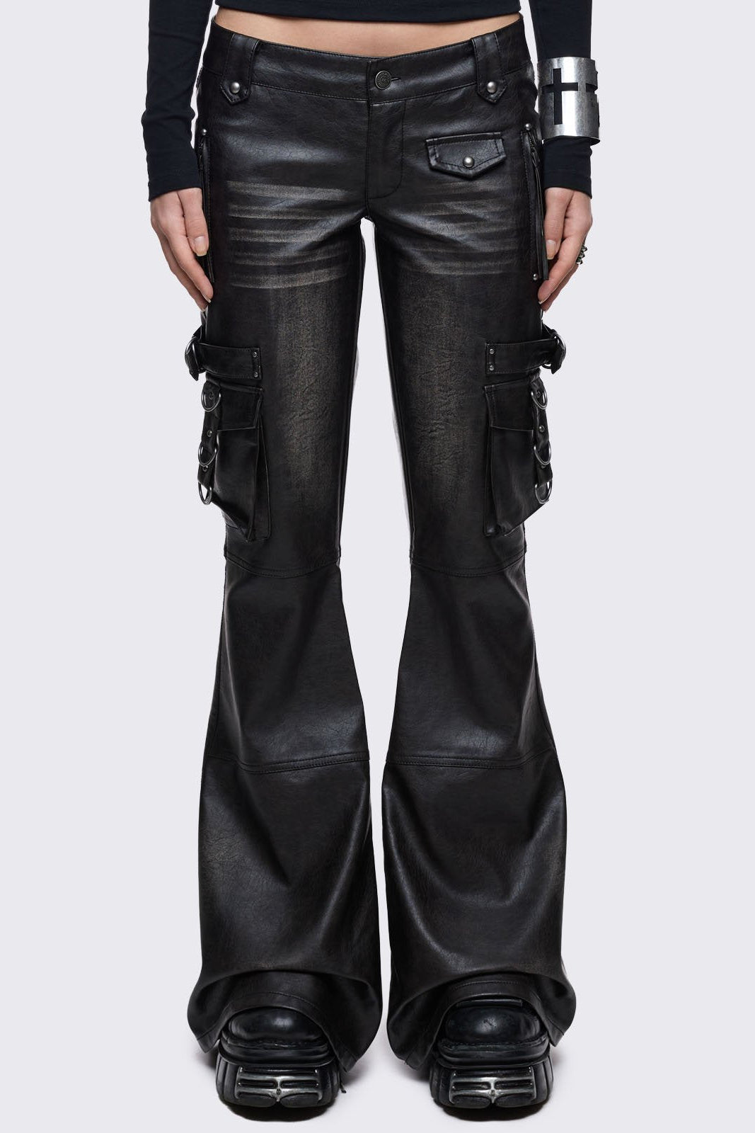 Low-rise black vegan leather pants with a dramatic flared leg, featuring oversized 3D cargo pockets with silver hardware and a vintage washed effect.