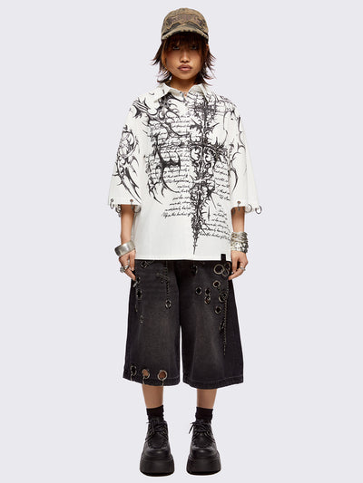 White oversized bowling shirt with black sigilism and lettering graphic print, eyelets with silver O-rings on sleeves and collar and more metal hardware details. 
