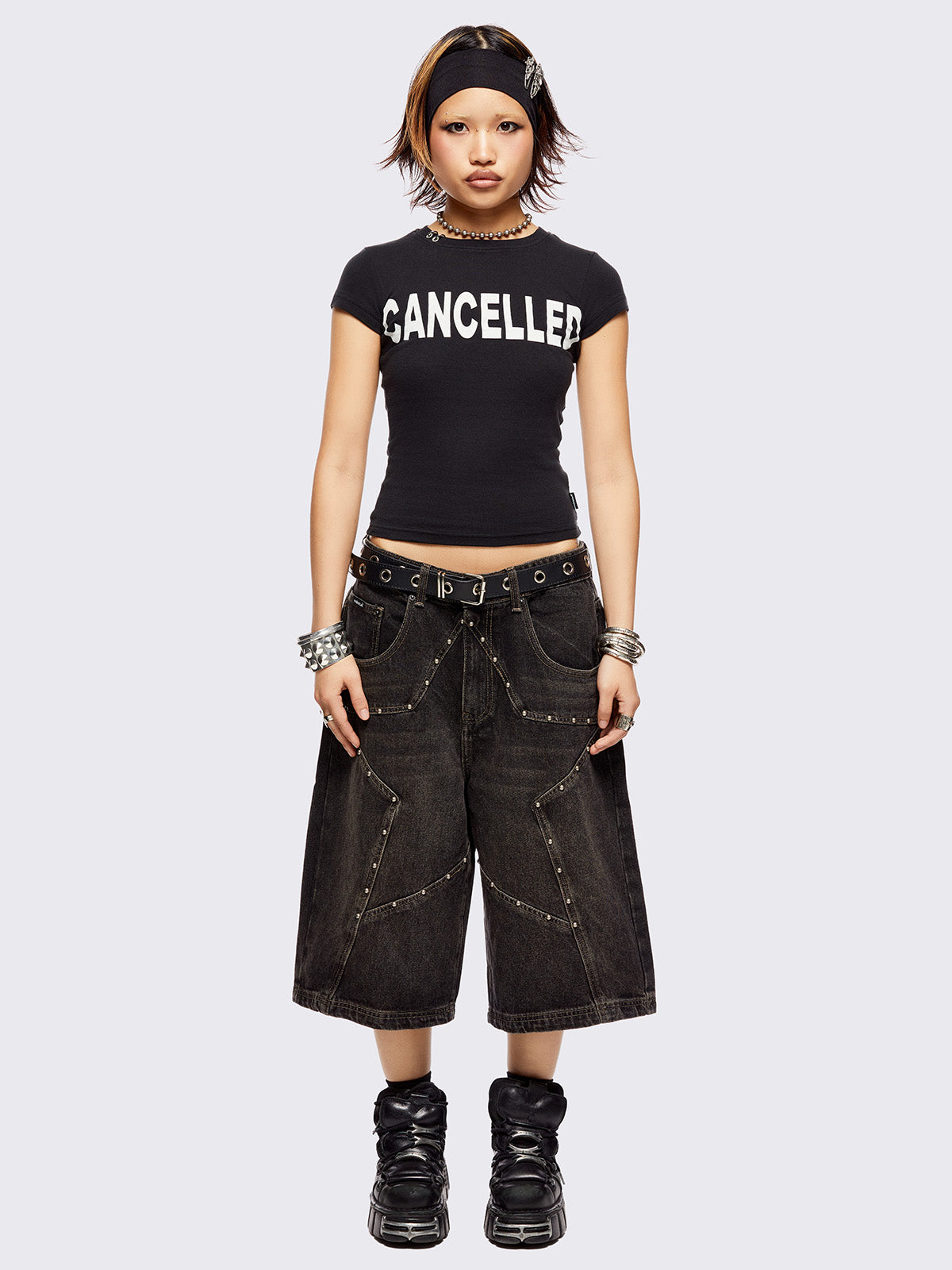 Black washed longline denim shorts with star-shaped stud and seam detail on front.