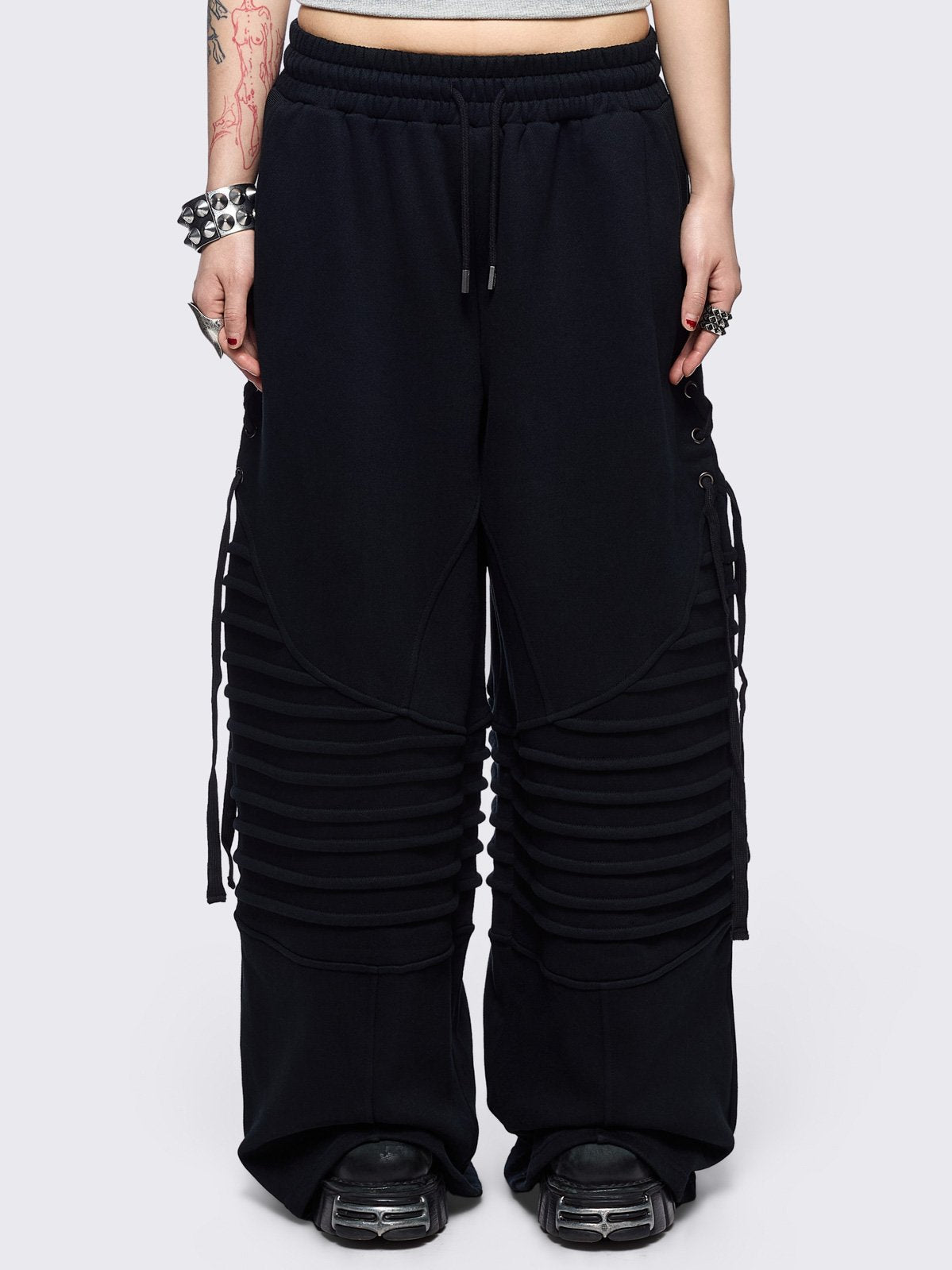 Black wide leg sweatpants featuring moto pintuck panels and lace-up details. 